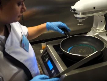 Sarah, gagnante du concours régional, prépare des anneaux olympiques avec du colorant pour décorer son « dessert de champion »